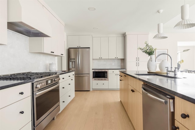 4508 Thunder Rd, Dallas, TX 75244 - kitchen with stainless steel appliances, a sink, wall chimney range hood, dark countertops, and light wood-style flooring