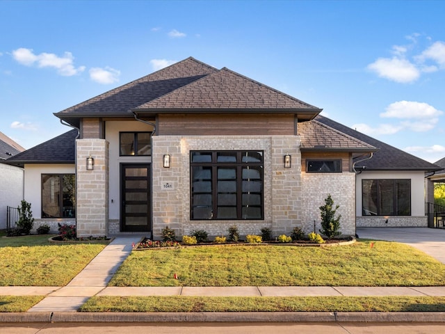 prairie-style home featuring roof with shingles and a front yard