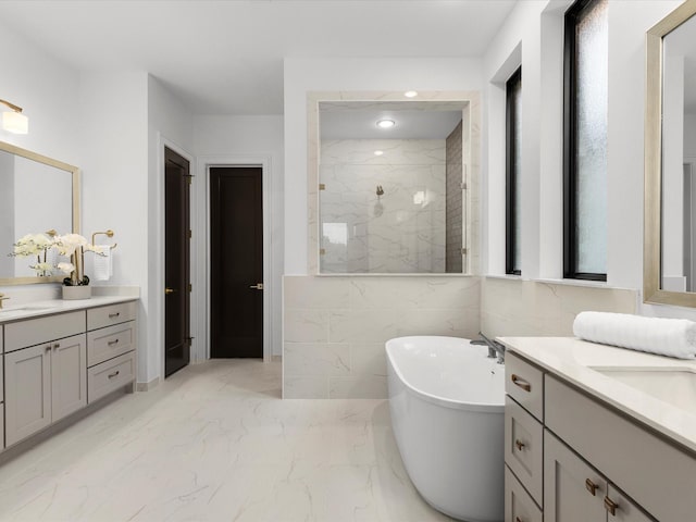 full bathroom with walk in shower, a sink, marble finish floor, two vanities, and a freestanding tub