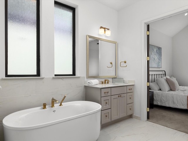 bathroom with a freestanding bath, marble finish floor, and vanity
