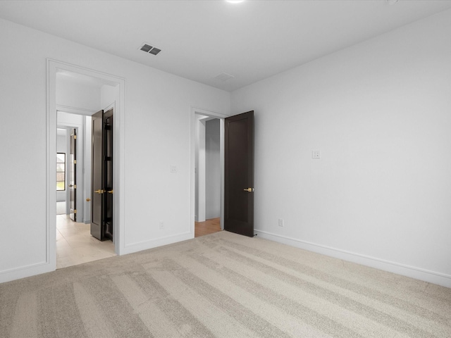 unfurnished bedroom with baseboards, visible vents, and light colored carpet