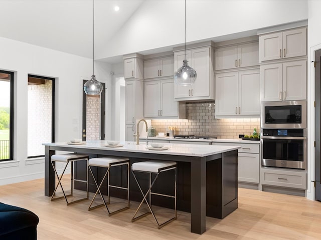 kitchen featuring backsplash, a breakfast bar, stainless steel oven, and a sink