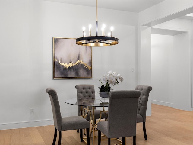 dining room featuring a chandelier, baseboards, and wood finished floors