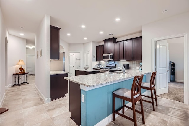 2828 Ainsworth Rd, Aubrey, TX 76227 - kitchen with appliances with stainless steel finishes, a sink, arched walkways, light stone counters, and a peninsula