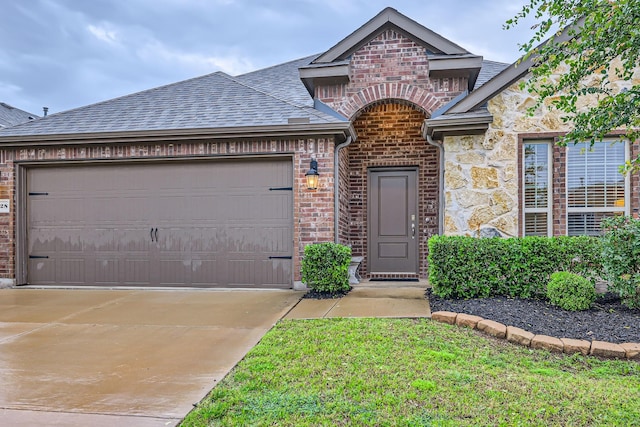 2828 Ainsworth Rd, Aubrey, TX 76227 - french country home with a shingled roof, a garage, concrete driveway, stone siding, and brick siding