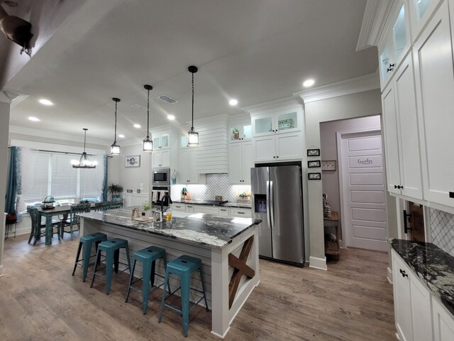 12890 County Road 463, Tyler, TX 75706 - kitchen with stainless steel appliances, ornamental molding, backsplash, white cabinets, and a kitchen breakfast bar