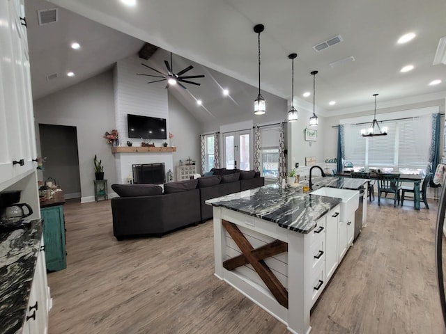 12890 County Road 463, Tyler, TX 75706 - kitchen with a ceiling fan, a large fireplace, light wood-type flooring, white cabinets, and dark stone counters