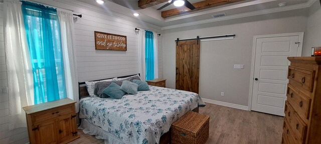12890 County Road 463, Tyler, TX 75706 - bedroom with a barn door, light wood-style flooring, wooden walls, baseboards, and ceiling fan