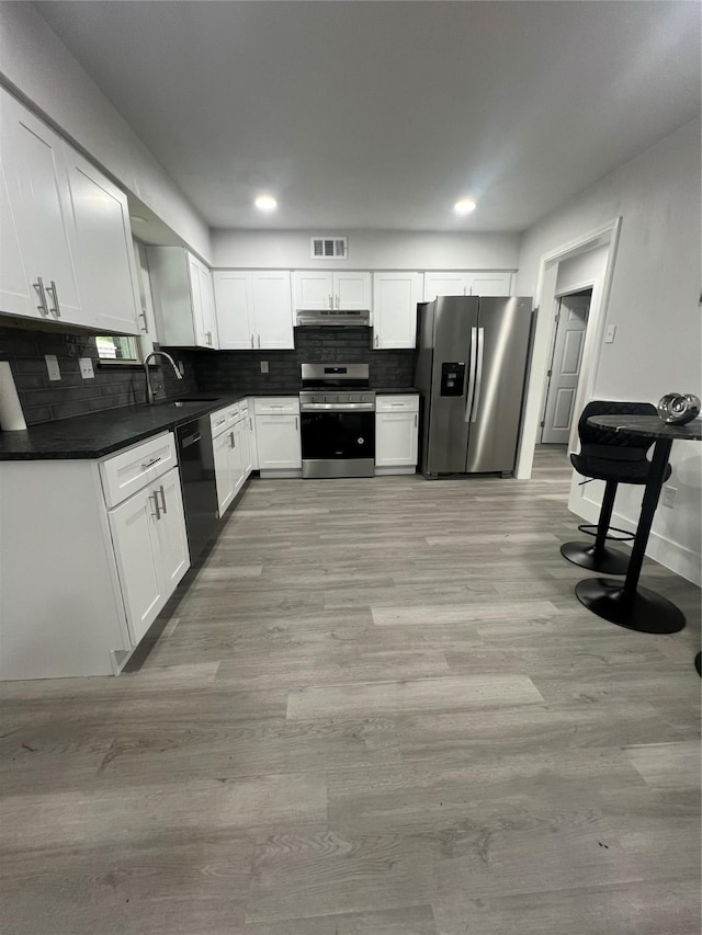 2721 San Marcus Ave, Dallas, TX 75228 - kitchen featuring appliances with stainless steel finishes, dark countertops, a sink, light wood finished floors, and backsplash