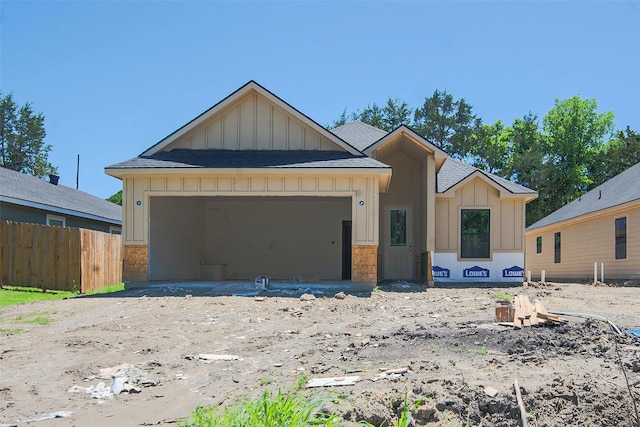 unfinished property with board and batten siding, a shingled roof, fence, and an attached garage