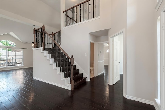 stairs with baseboards, high vaulted ceiling, a ceiling fan, and wood finished floors