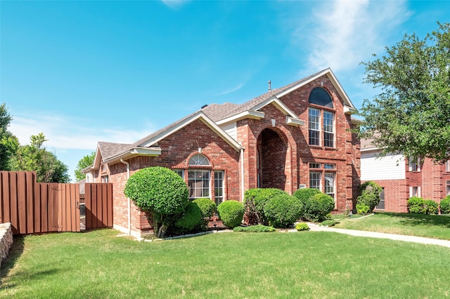 traditional-style home with fence, a front lawn, and brick siding