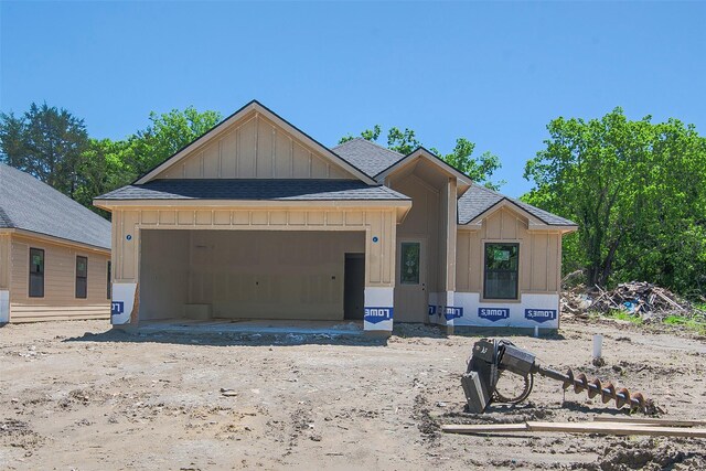 property under construction with board and batten siding, roof with shingles, and a garage