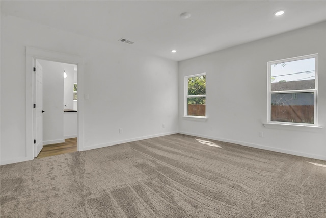 carpeted empty room with baseboards, visible vents, and recessed lighting