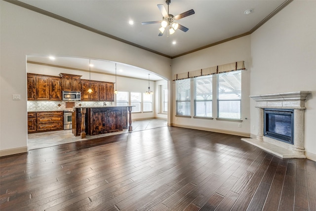 503 Olive Trl, Forney, TX 75126 - unfurnished living room featuring a glass covered fireplace, dark wood finished floors, ceiling fan, baseboards, and ornamental molding