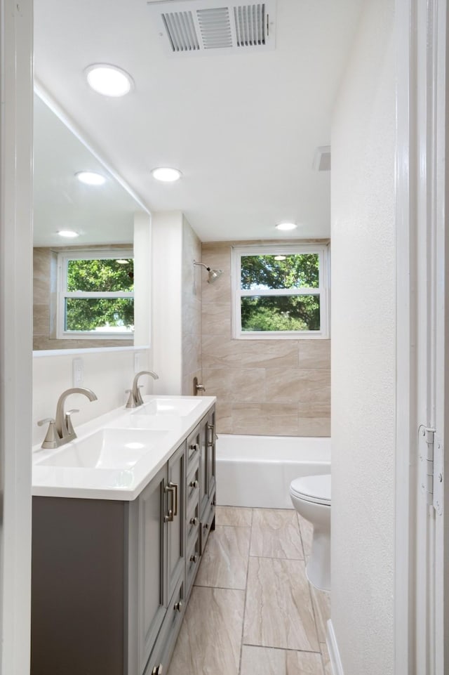 full bathroom with double vanity, toilet, a sink, bathing tub / shower combination, and visible vents