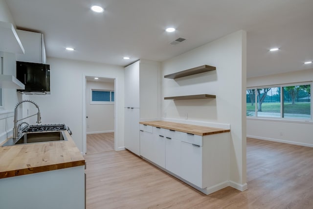 kitchen with light wood-type flooring, visible vents, a sink, and butcher block countertops