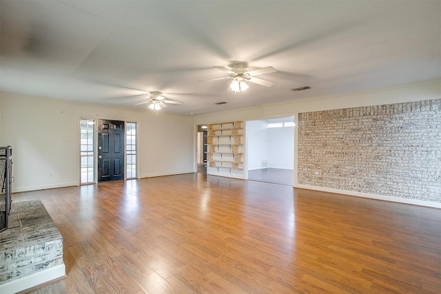 unfurnished living room with wood finished floors, visible vents, crown molding, a ceiling fan, and baseboards
