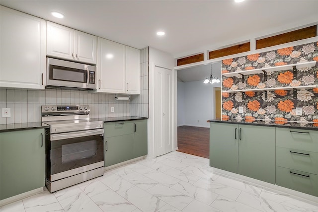 kitchen featuring dark countertops, white cabinets, appliances with stainless steel finishes, and a chandelier