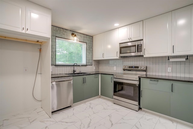 kitchen featuring a sink, dark countertops, stainless steel appliances, white cabinetry, and marble finish floor