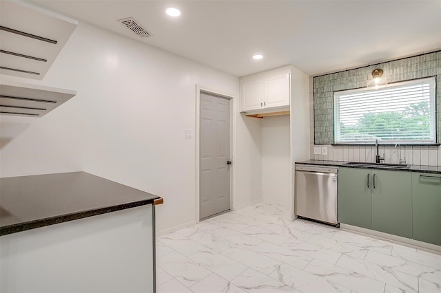 kitchen featuring dark countertops, stainless steel dishwasher, visible vents, and a sink