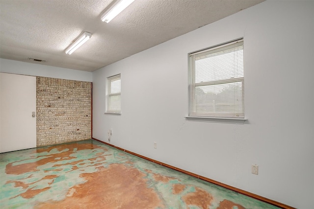 empty room with baseboards, concrete flooring, visible vents, and a textured ceiling