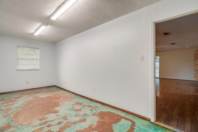 unfurnished room featuring baseboards, visible vents, a textured ceiling, and wood finished floors