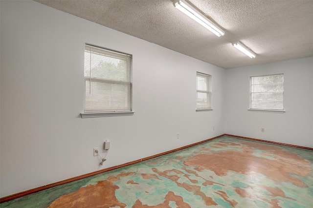 spare room with a textured ceiling and baseboards