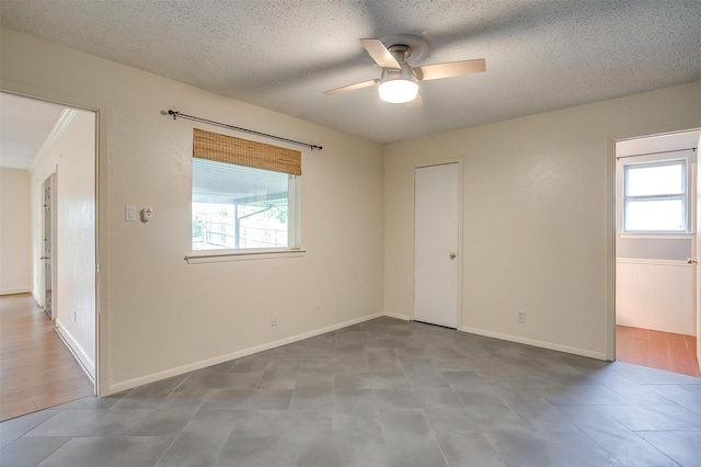 empty room with a textured ceiling and a ceiling fan