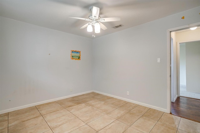 spare room with light tile patterned floors, baseboards, visible vents, and a ceiling fan