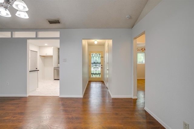 foyer featuring light wood-type flooring, a notable chandelier, visible vents, and baseboards