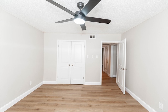unfurnished bedroom featuring light wood finished floors, a textured ceiling, baseboards, and visible vents