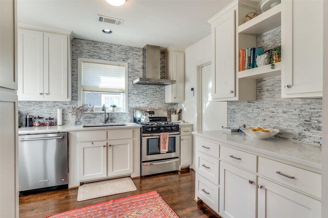 kitchen featuring a sink, stainless steel appliances, tasteful backsplash, visible vents, and wall chimney exhaust hood