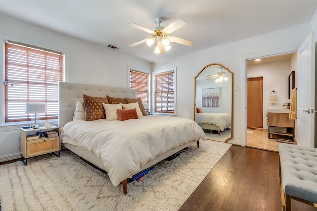 bedroom featuring multiple windows, a ceiling fan, visible vents, and wood finished floors