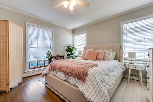 bedroom featuring baseboards, multiple windows, ornamental molding, and wood finished floors