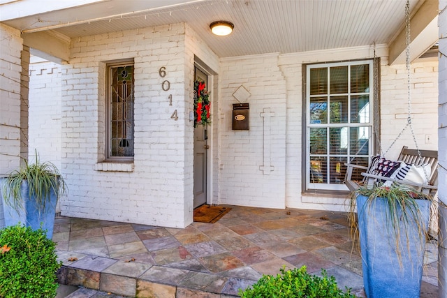 property entrance featuring a porch and brick siding