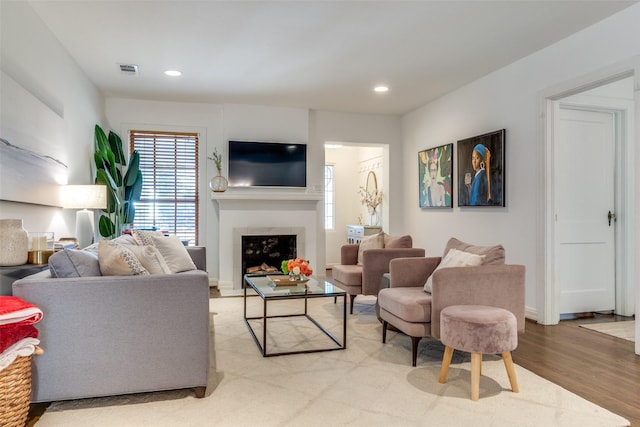 living room with light wood-type flooring, visible vents, a fireplace, and recessed lighting