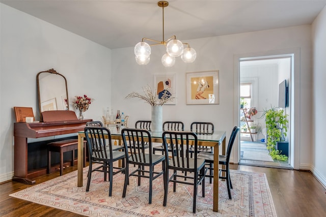 dining room with a chandelier, baseboards, and wood finished floors