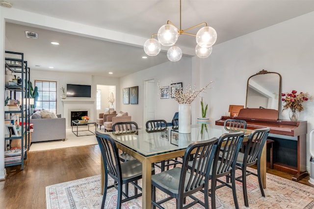 dining space with wood finished floors, a fireplace, visible vents, a chandelier, and recessed lighting