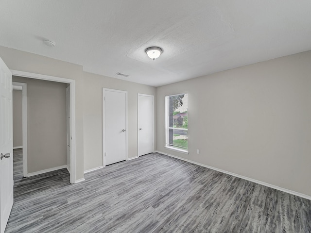 4250 Leland College Dr, Dallas, TX 75241 - unfurnished bedroom featuring a textured ceiling, visible vents, wood finished floors, and baseboards