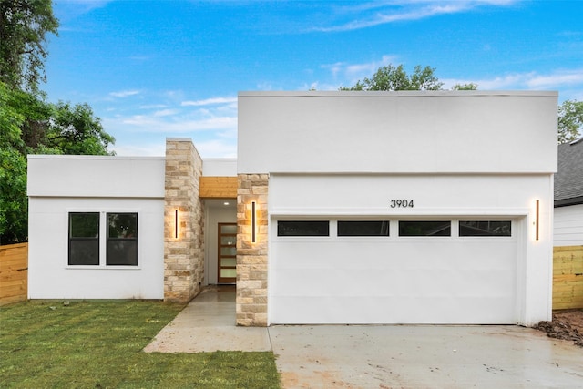 3904 De Maggio Ave, Dallas, TX 75210 - contemporary home featuring fence, an attached garage, stone siding, driveway, and stucco siding