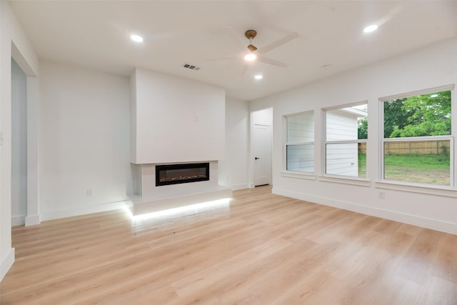 3904 De Maggio Ave, Dallas, TX 75210 - unfurnished living room featuring light wood-style flooring, a ceiling fan, a glass covered fireplace, and recessed lighting