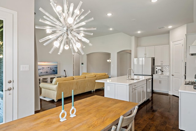 kitchen with a sink, arched walkways, dark wood-style floors, and a notable chandelier