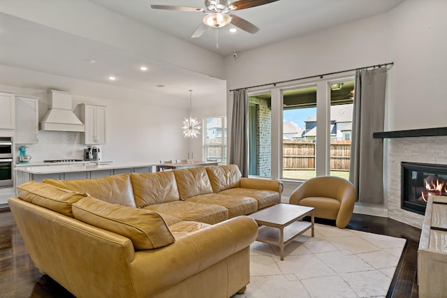 living room featuring a fireplace, recessed lighting, ceiling fan with notable chandelier, and wood finished floors