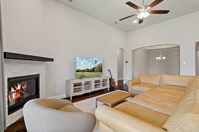 living room with baseboards, arched walkways, ceiling fan with notable chandelier, and wood finished floors