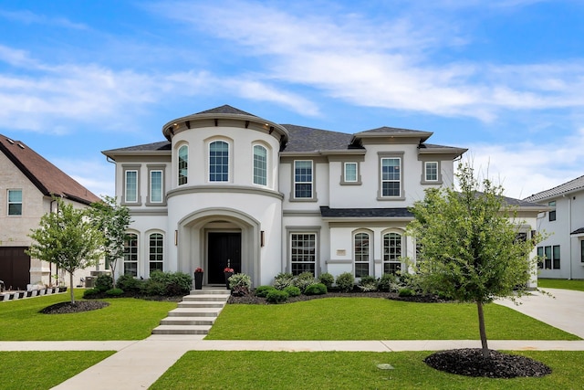 view of front of home featuring stucco siding, a front lawn, and roof with shingles