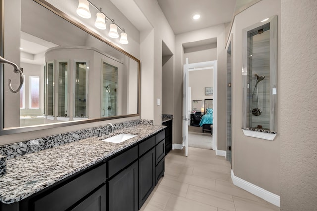 ensuite bathroom featuring an enclosed shower, vanity, and baseboards