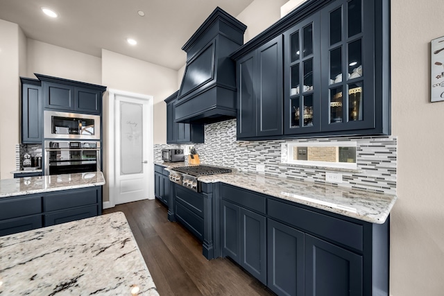 kitchen with stainless steel appliances, blue cabinets, custom range hood, backsplash, and recessed lighting