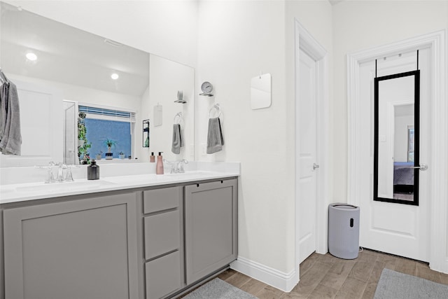 bathroom featuring double vanity, wood finished floors, baseboards, and a sink