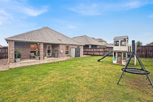 rear view of house featuring a patio, a playground, a fenced backyard, a yard, and roof with shingles